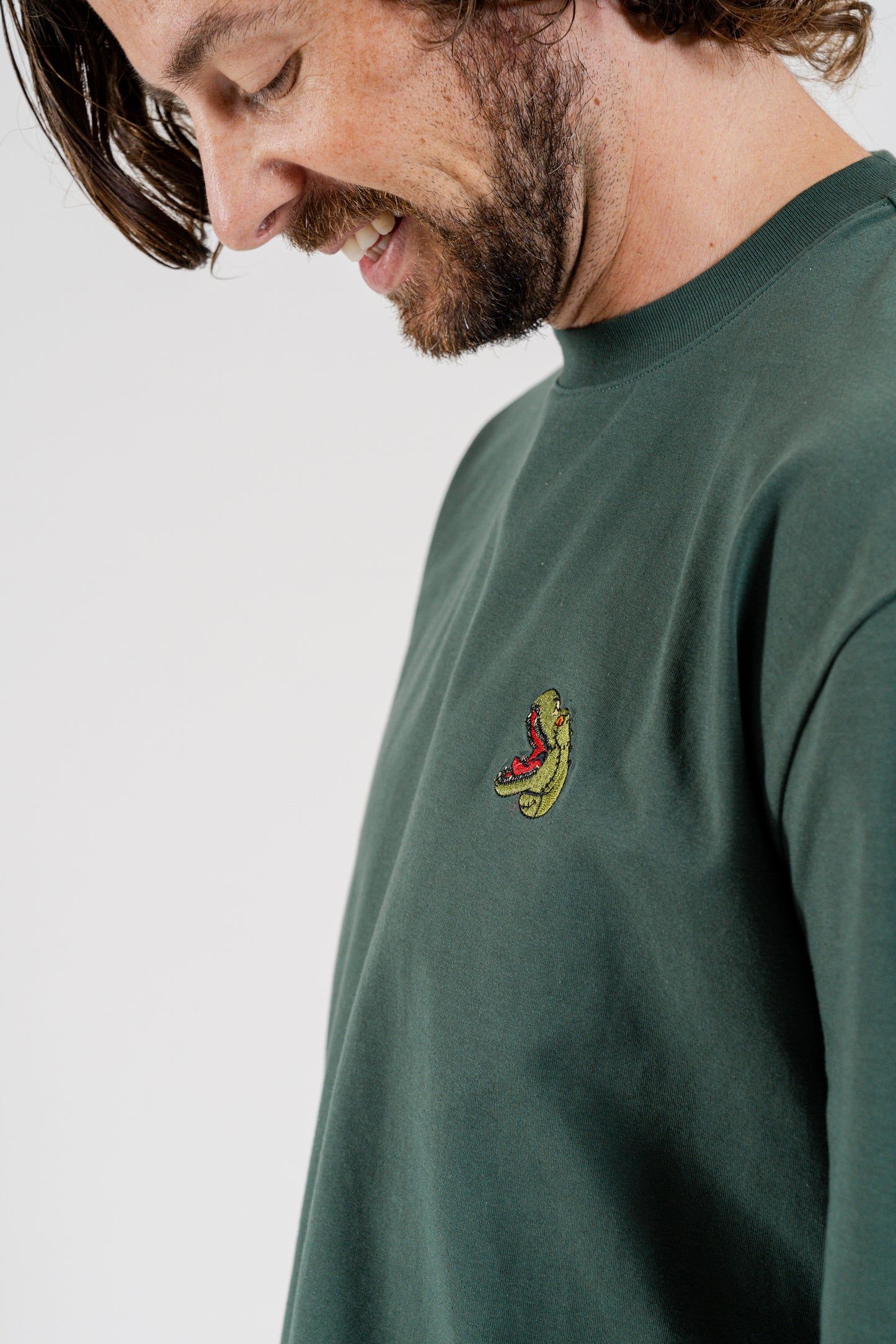 Man wearing green mens dinosaur themed long sleeve sweater with embodied rexy dinosaur