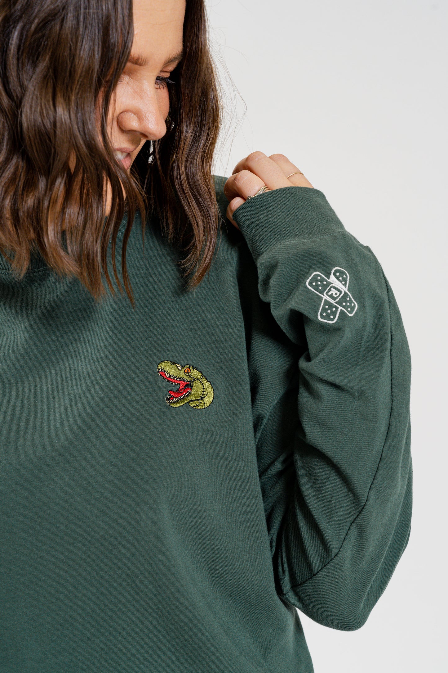 Woman wearing green dinosaur themed sweater with embodied rexy dinosaur